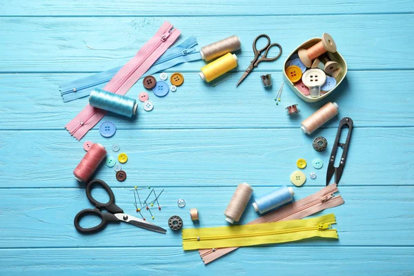 Frame made of tailoring accessories on wooden background, top view