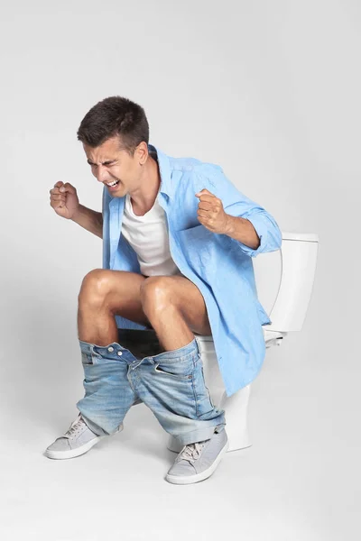 Junger Mann Mit Durchfall Auf Toilettenschüssel Vor Grauem Hintergrund — Stockfoto