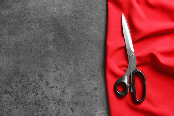 Makas ve kırmızı kumaş tablo, üstten görünüm. Dikiş aksesuarları