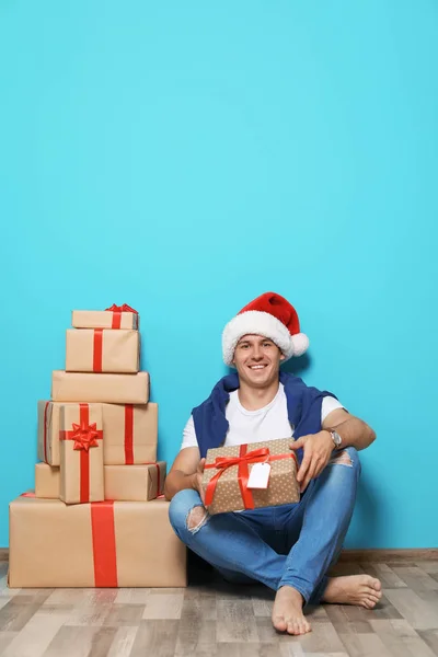 Молодой Человек Рождественскими Подарками Возле Цветной Стены — стоковое фото