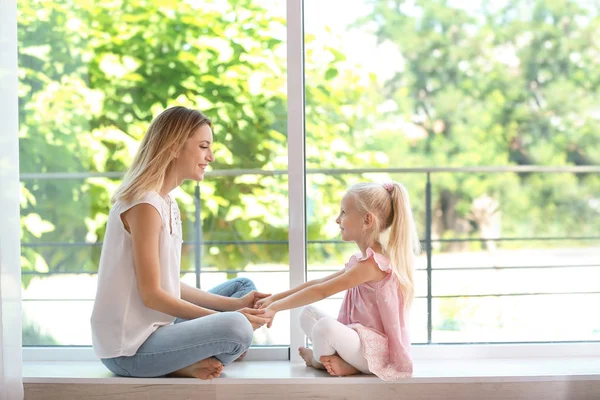 Sevimli küçük kız evde pencere yanında olan kadın