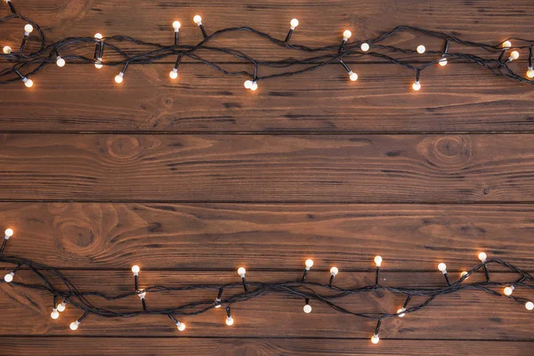 Ahşap arka plan, üstten görünüm parlak Noel ışıkları
