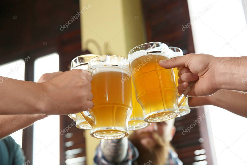 Friends clinking glasses with beer in pub