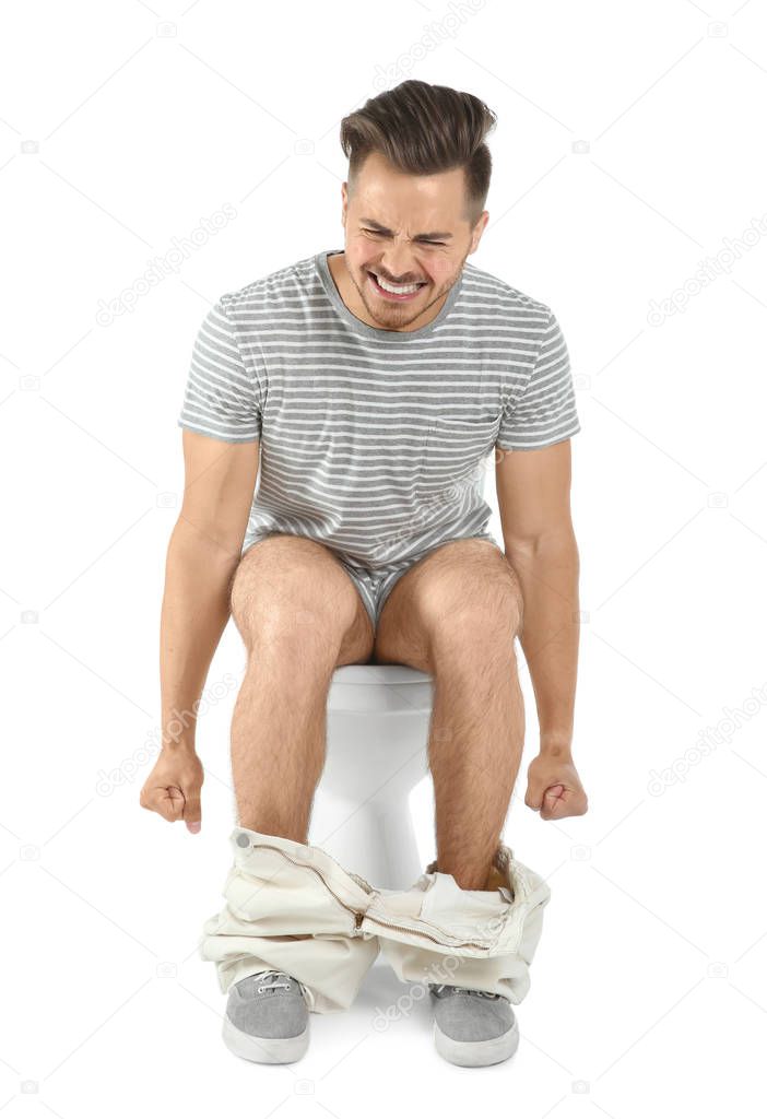 Young man suffering from diarrhea on toilet bowl. Isolated on white