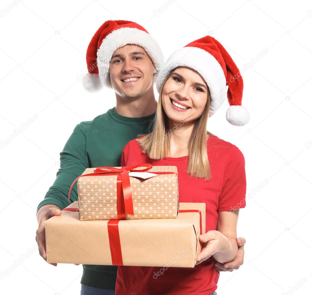 Young couple with Christmas gifts on white background