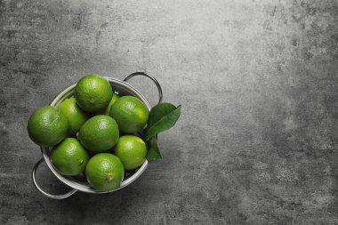 Kevgir ile olgun taze limes gri arka planda, üstten görünüm
