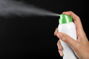 Genç kadın deodorant siyah arka plan üzerine püskürtme