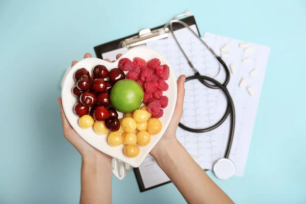Ärztin Hält Teller Mit Frischen Früchten Über Farbigem Hintergrund Draufsicht — Stockfoto