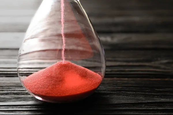 Hourglass with flowing sand on table, closeup. Time management