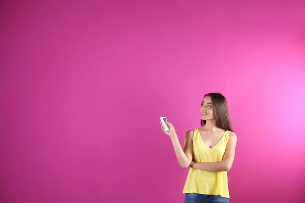 Junge Frau Schaltet Klimaanlage Auf Farbigem Hintergrund Ein — Stockfoto