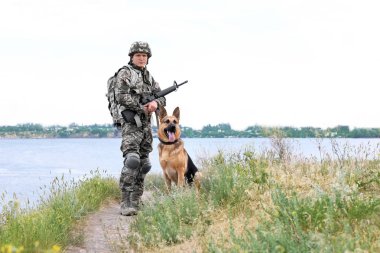 Alman çoban köpeği Nehri yakınında ile askeri üniformalı erkeklere