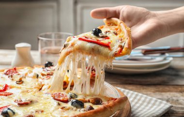 Lezzetli sıcak pizza dilim masa üzerinde closeup tutan kadın