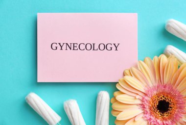 Card with word GYNECOLOGY, tampons and flower on color background, top view clipart
