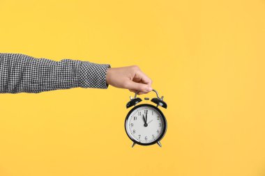 Saat renk arka plan üzerinde tutan genç kadın. Zaman yönetimi