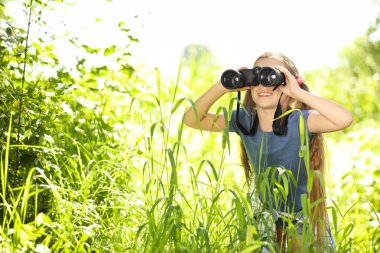 Dürbün açık havada olan küçük kız. Yaz Kampı