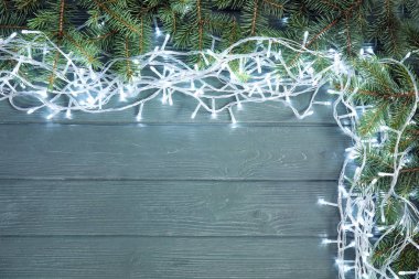 Parlak Noel ışıkları ve köknar ahşap arka plan, üstten görünüm dallarda