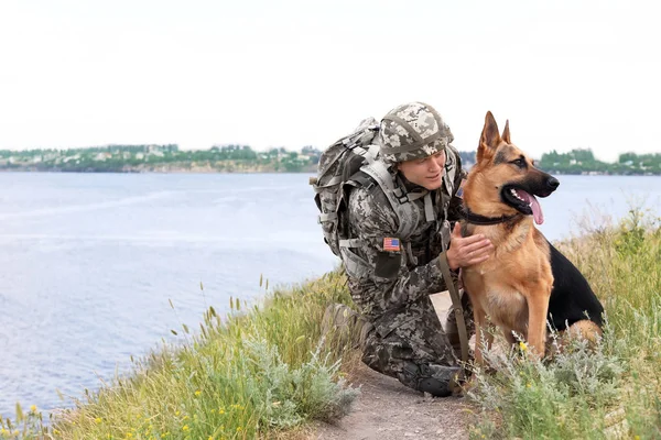 Alman çoban köpeği Nehri yakınında ile askeri üniformalı erkeklere