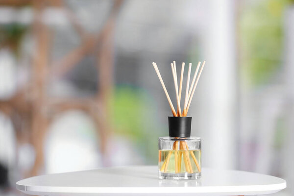 Aromatic reed air freshener on table against blurred background