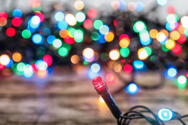 Glowing colorful Christmas lights on table, closeup