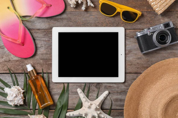 Flat lay composition with beach objects and tablet on wooden background