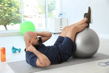 Egzersiz fitness topu içinde jimnastik salonu ile yapan kilolu erkek