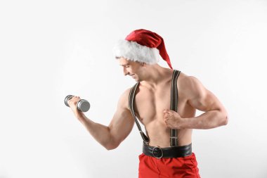Beyaz arka plan üzerinde halter ile Noel Baba şapkalı kaslı delikanlı
