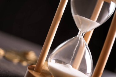 Hourglass with flowing sand on table, closeup. Time management clipart
