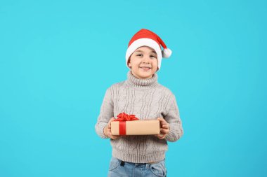 Noel Baba şapkası renk arka plan üzerinde Noel hediye ile şirin küçük çocuk