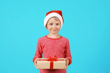 Noel Baba şapkası renk arka plan üzerinde Noel hediye ile şirin küçük çocuk