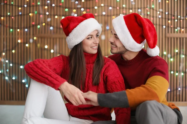 Pareja Joven Sombreros Santa Sobre Fondo Borroso Luces Celebración Navidad —  Fotos de Stock