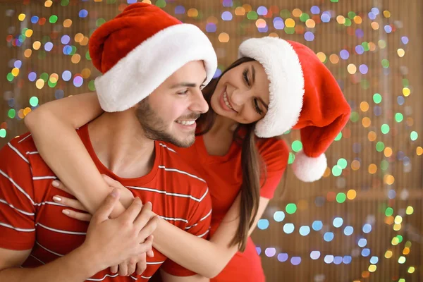 Noel Baba Şapkaları Bulanık Işıklar Arka Plan Üzerinde Genç Çift — Stok fotoğraf
