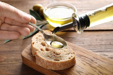 Taze zeytin yağı içine kaşık masa, tatlı ekmek üzerine dökülen adam