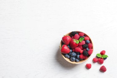 Ahududu ve ahşap masa, üstten görünüm üzerinde farklı meyveler ile kase