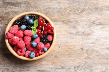 Ahududu ve ahşap masa, üstten görünüm üzerinde farklı meyveler ile kase