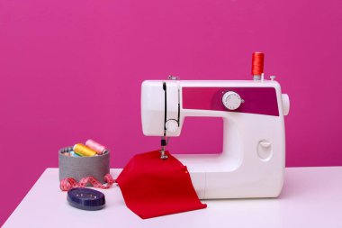 Modern sewing machine on table against color background clipart