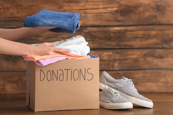 Mujer Voluntaria Poniendo Ropa Caja Donación Sobre Fondo Madera — Foto de Stock