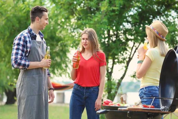 Young people having barbecue with modern grill outdoors