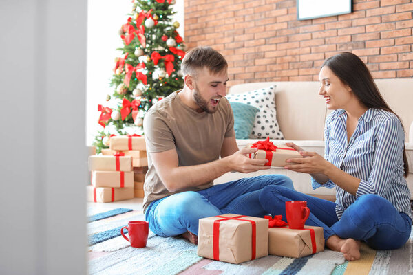 Happy young couple with Christmas gifts at home