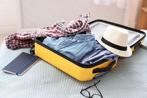Open suitcase with packed clothes on bed