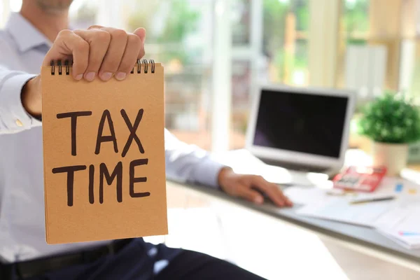 Homem Segurando Notebook Com Palavras Tax Tempo Dentro Casa — Fotografia de Stock