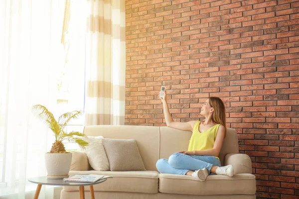 Woman with air conditioner remote at home