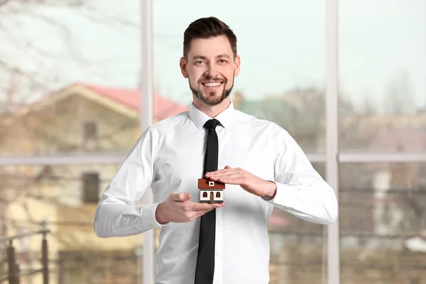 Real Estate Agent Holding House Model Indoors — Stock Photo, Image