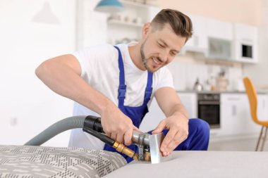 Kuru temizleme işçisi kanepedeki kiri temizliyor.