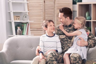 Onun çocukları evde kanepe ile askeri üniformalı genç adam