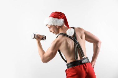 Beyaz arka plan üzerinde halter ile Santa şapka genç kaslı adam