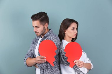 Renk arka plan üzerinde yırtık kağıt kalpli genç çift. İlişki sorunları