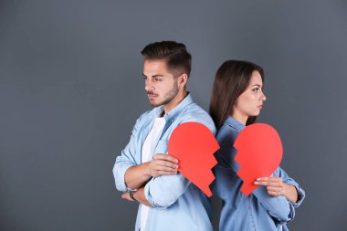 Gri arka plan üzerinde yırtık kağıt kalpli genç çift. İlişki sorunları