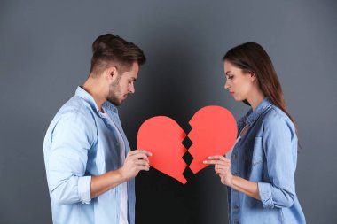 Gri arka plan üzerinde yırtık kağıt kalpli genç çift. İlişki sorunları