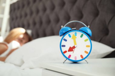 Analog alarm saat ve arka plan üzerinde bulanık uykulu kadın. Günün saati