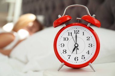 Analog alarm saat ve arka plan üzerinde bulanık uykulu kadın. Günün saati